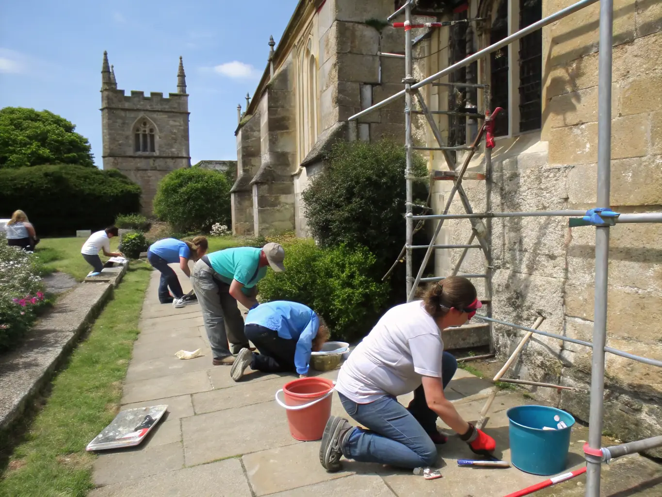 A group of people participating in a hands-on restoration workshop, carefully working on a historical building facade, showcasing LUNE RM's commitment to preserving cultural heritage.